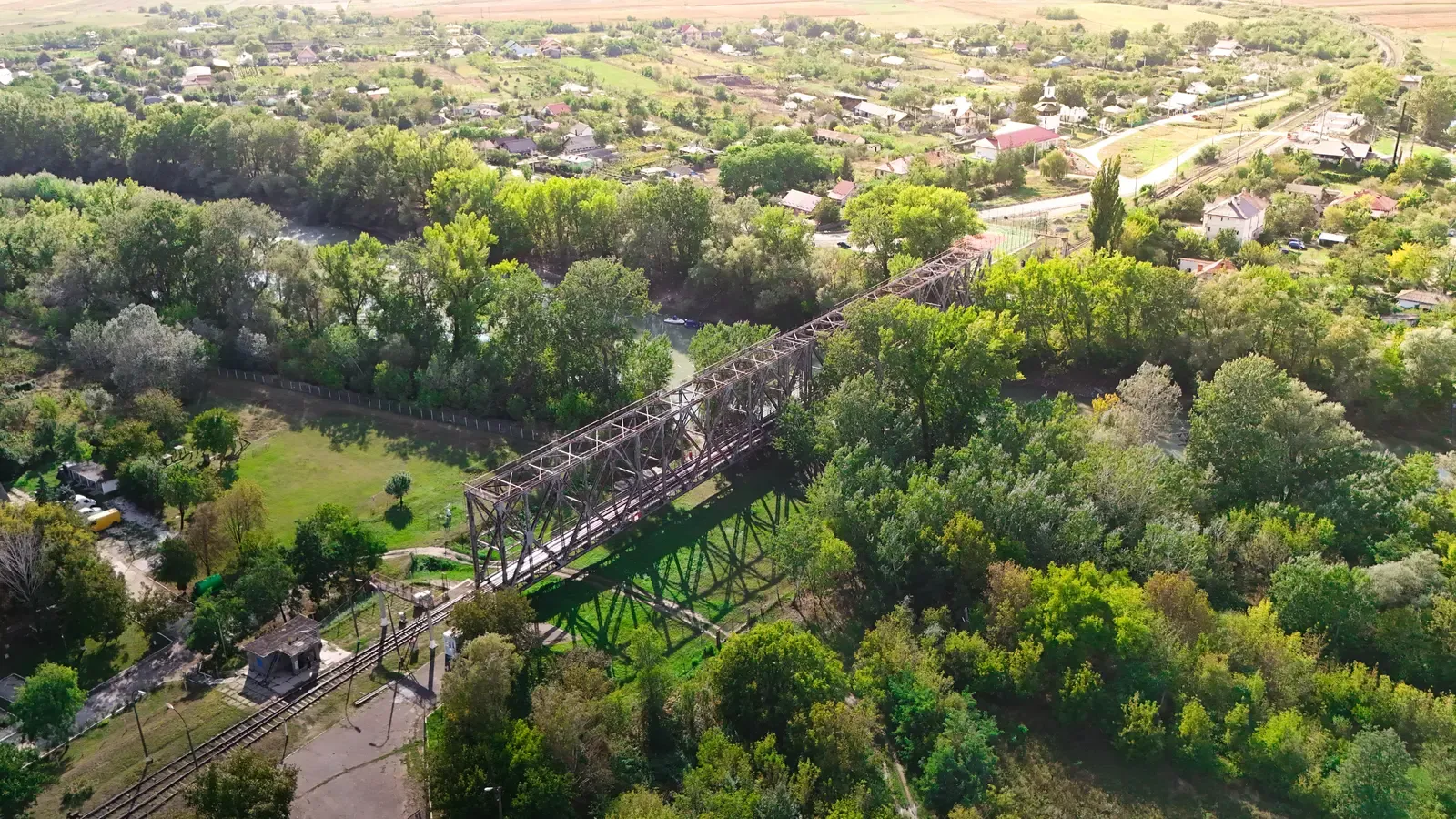 Vedere aeriană a podului feroviar de peste Prut de la Ungheni — o construcție metalică în grinzi cu zăbrele, singura trecere cu trenul dintre Republica Moldova și România, cu calea ferată și case pe cele două maluri.