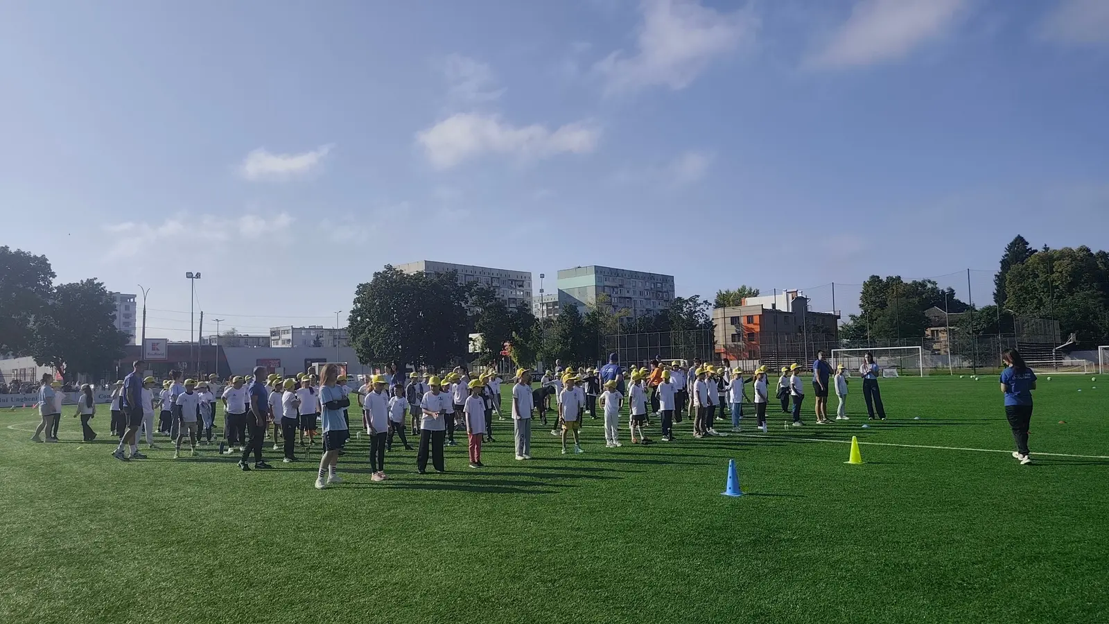Copii în echipament sportiv pe terenul Stadionului Municipal Ungheni, într-o zi însorită de vară.
