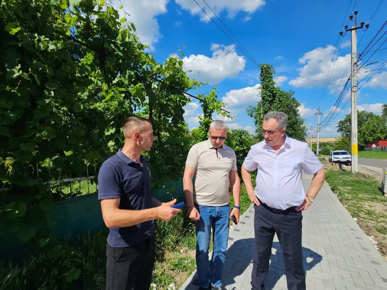 Primarul Vitalie Vrabie, în cămașă albă, discută cu doi bărbați pe trotuarul nou pavat de pe strada Ștefan cel Mare, în timpul inspecției șantierului.
