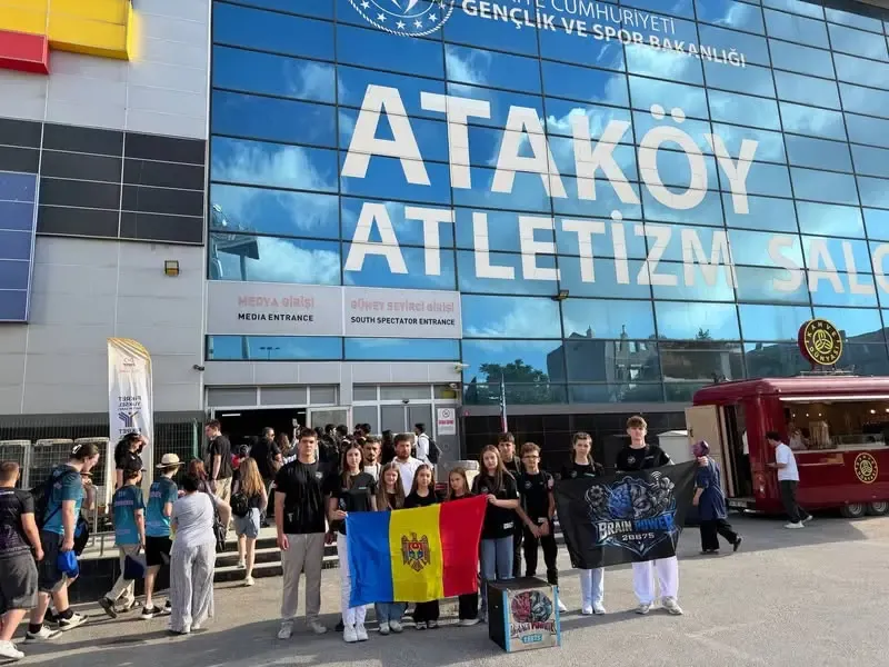 Elevii echipei „Brain Power”, cu un drapel al Republicii Moldova și cutia de transport a robotului, în fața clădirii Sălii de Atletism din Ataköy, Istanbul.