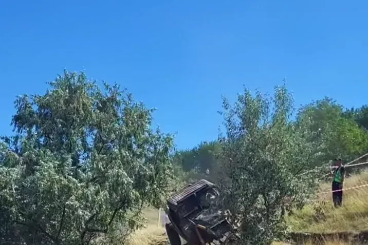 Vehicul off-road escaladează un taluz abrupt pe traseul de trial, ridicând un nor dens de praf, cu bandă de siguranță și spectatori pe margine